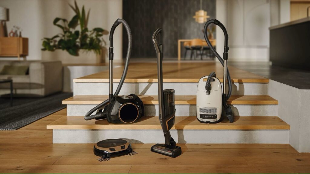 Four different Miele vacuums are arranged on a staircase of a home.